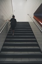 Child with a backpack climbing a flight of stairs.