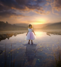 a young girl standing in a pond 