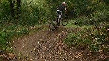 man riding a bicycle through a forest on a trail 