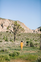 a woman in an orange dress walking in the desert 
