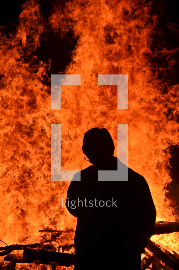 silhouette of a man in front of a raging fire