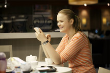 Young woman chatting on smartphone in cafe
