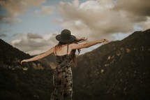 a woman on a mountaintop with outstretched arms 