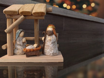 A wooden nativity scene on a glass table.
