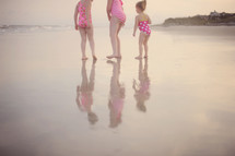 children standing on wet sand at a beach 