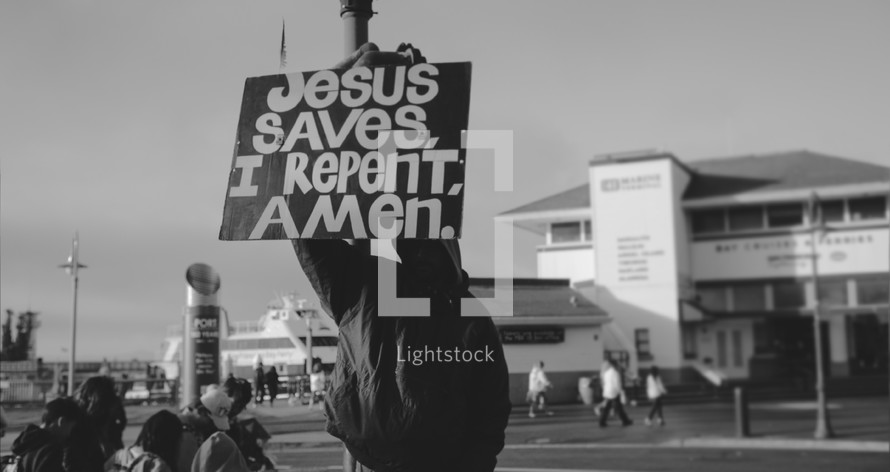 man holding a sign Jesus Saves I repent Amen