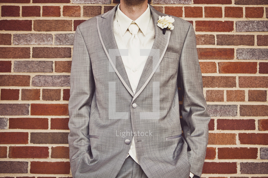A groom standing in front of a brick wall