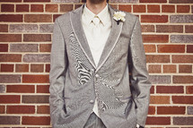 A groom standing in front of a brick wall