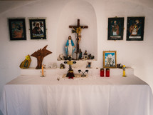an altar in a small chapel with a statue of mary a crucifix, candles