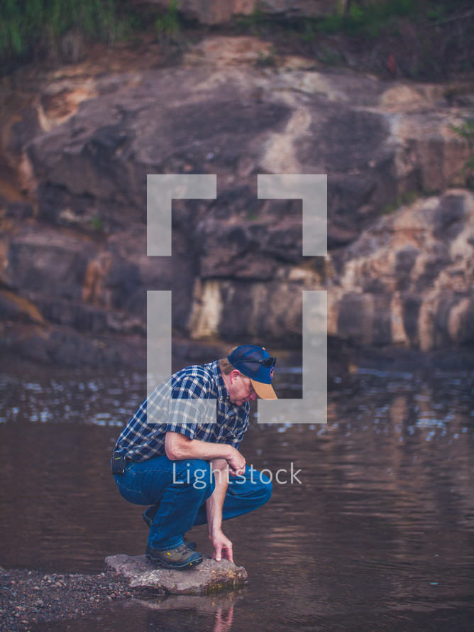 a man standing on a rock near a stream 