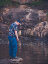 a man standing on a rock beside a stream 