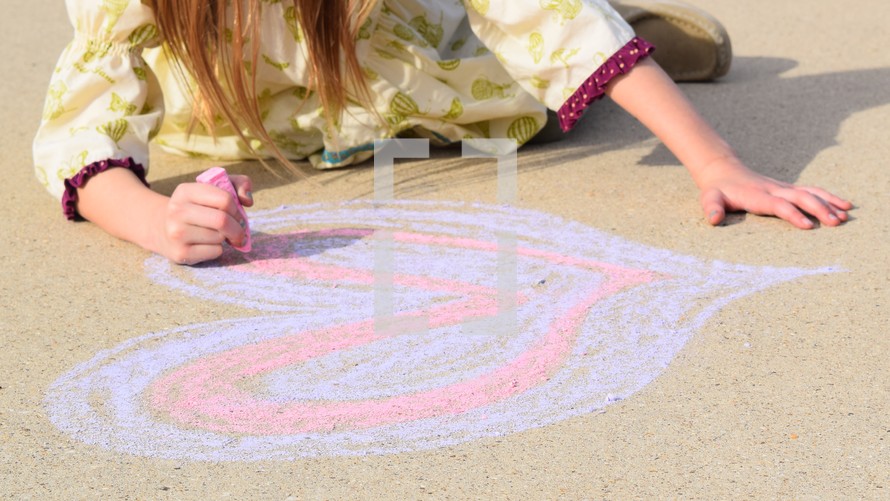 a little girl drawing a Valentine's heart on concrete with sidewalk chalk 