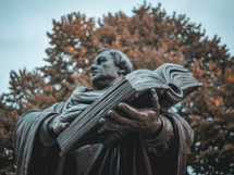 A statue of Martin Luther holding a bible in focus
