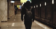 Man with headphones and backpack walking on subway platform