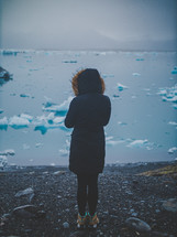 a woman looking out at ice chunks in water 