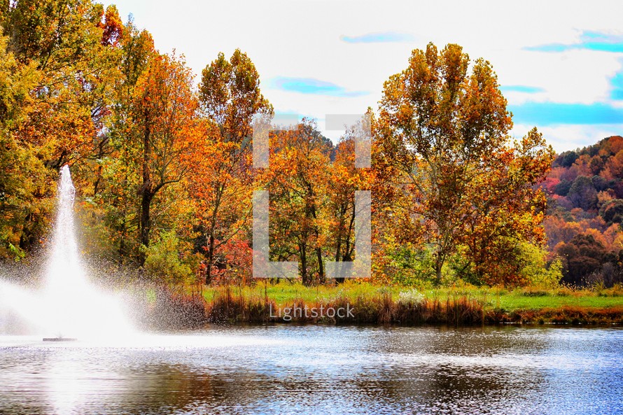 fountain in a lake surrounded by autumn trees