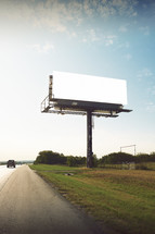 a car passing a blank billboard 