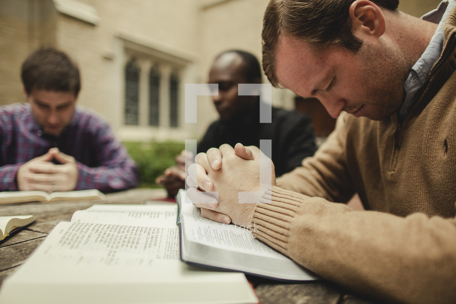 A group of men praying during a Bible study