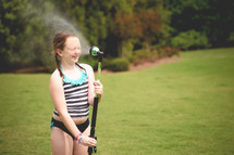 child spraying a hose on a summer day 