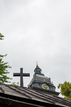 A cross in front of a church steeple.