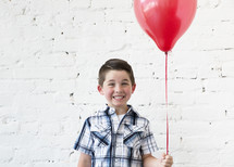 a boy child holding a red balloon 