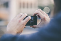 Hands holding a cell phone, taking a photo.