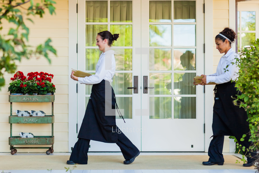 caterers  servers carrying plates across porch. 
