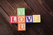 "Love You" spelled out with children's colorful wooden blocks.