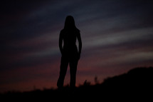 silhouette of young woman on a mountaintop at sunset 