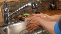A woman washing her hands at a kitchen sink