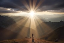 Man standing on the top of the mountain and looking at the sun, with Sun Rays