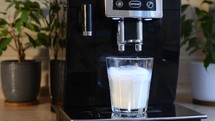 cooking cappuccino in a coffee machine. Coffee is poured into harvested foamed milk. Preparation of multi-layer cappuccino in a coffee machine. Coffee is poured into harvested foamed milk