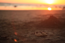 shoes on the sand on a beach at sunset 