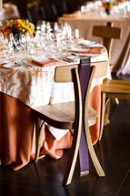 Empty formal dining table party event wood chair made from wine barrel, orange linens flatware, wine glasses