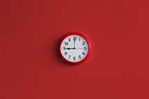 A red wall clock on a bright red wall.