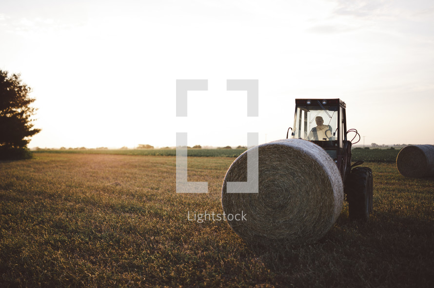a tractor collecting bales of hay 