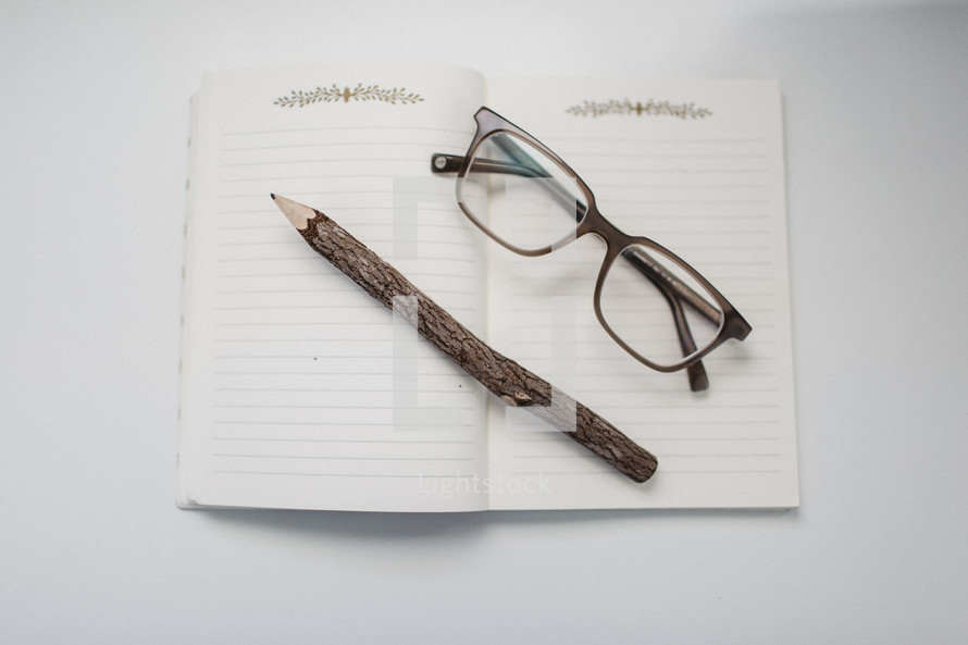 reading glasses and carved pencil on a notebook 