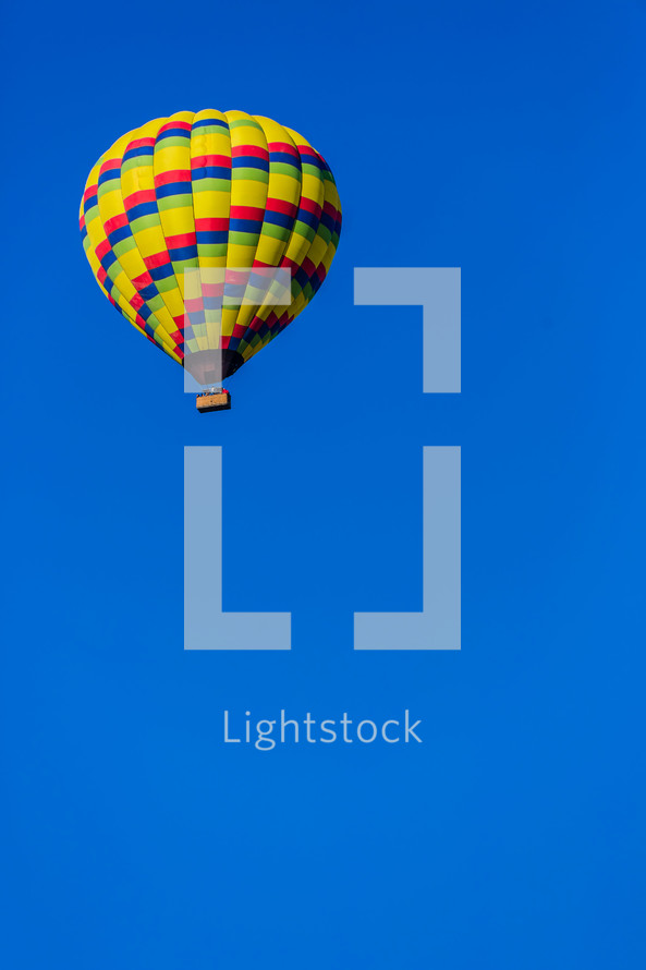 A brightly colored hot air balloon in a blue sky one