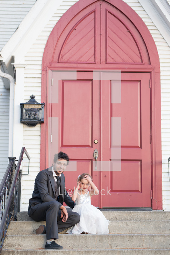 father and daughter sitting on the steps of a church 