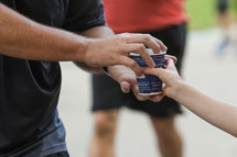 child passing out water to a runner