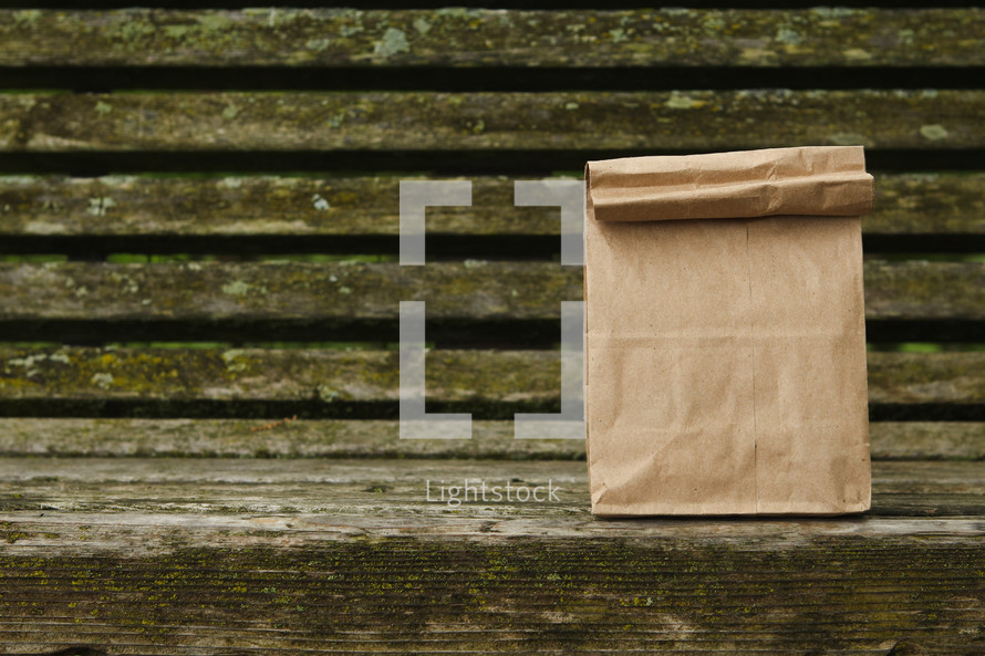 brown lunch bag on a wood bench 