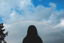silhouette of a child under a rainbow 