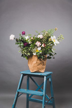 a flower arrangement on a blue ladder 
