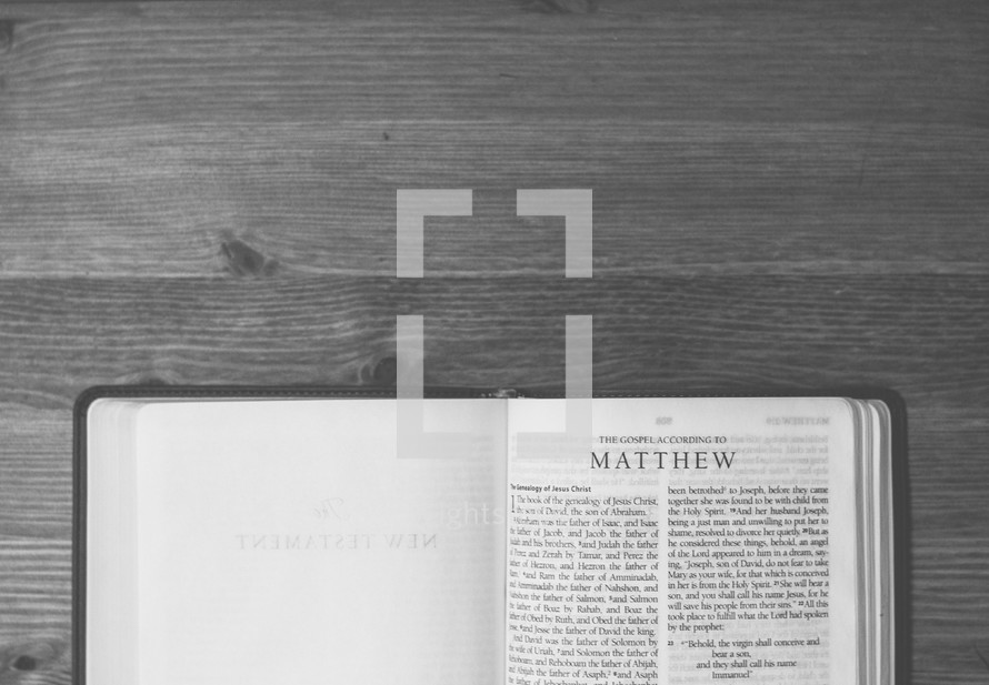 Bible open to Matthew on a wooden table.