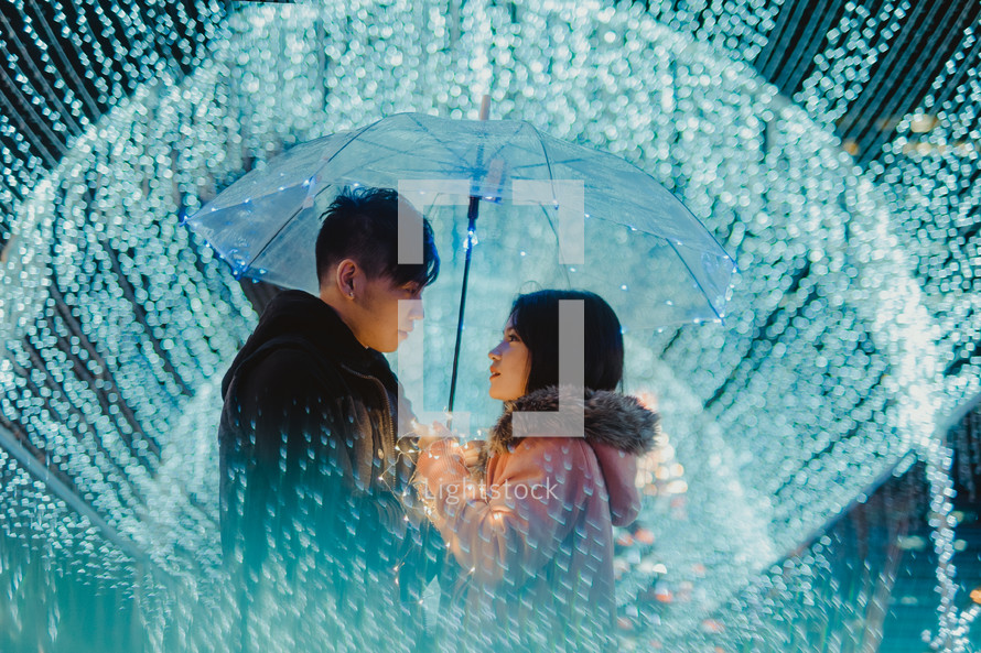 a couple standing under blue lights and an umbrella 