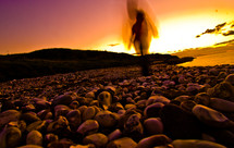 blurry shape of a person walking on a stone shore