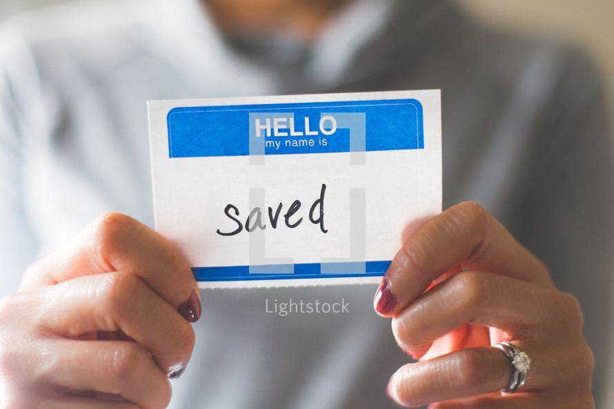 woman holding a name tag with the word saved 