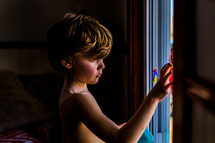 child finger painting on a window 