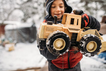 boy playing with a truck in the snow 