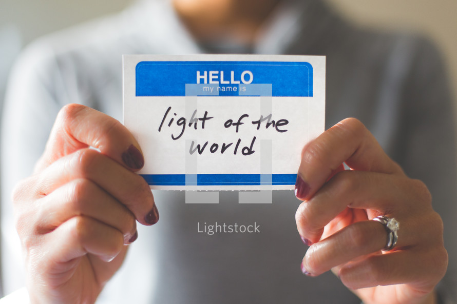 woman holding a name tag with the word light of the world 